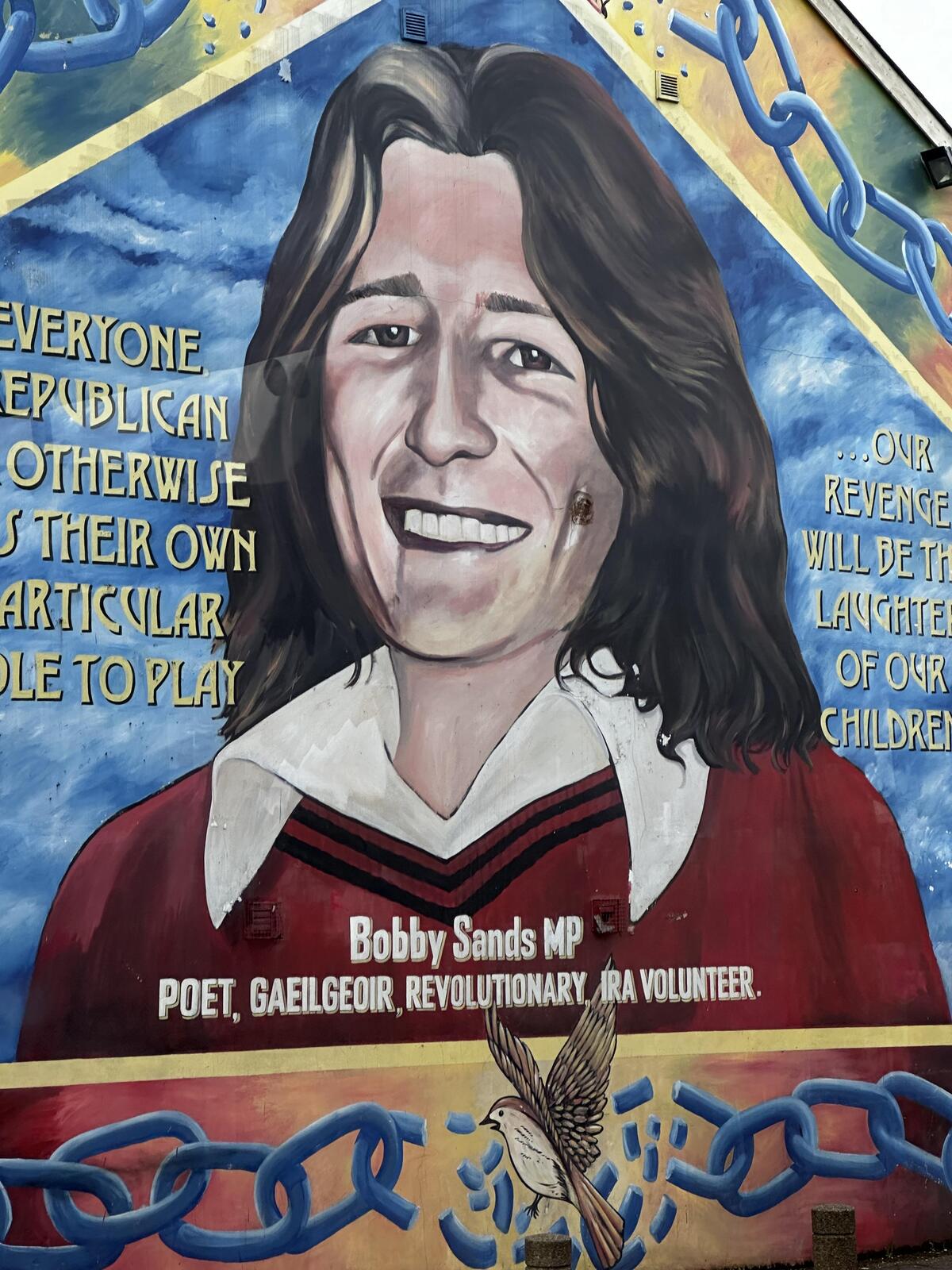 Bobby Sands memorial gravestone with flowers and Irish flag